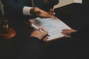 Business and lawyers discussing contract papers with brass scale on desk in office. Law, legal services, advice, justice and law concept picture with film grain effect photo