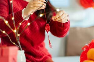 Asian Woman decorated house for Chinese New Year Celebrations. putting traditional pendant to the Chinese Lunar New Year for good luck. Chinese word means blessing photo