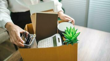 Business woman sending resignation letter and packing Stuff Resign Depress or carrying business cardboard box by desk in office. Change of job or fired from company photo