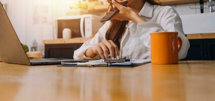 el retrato de una joven mujer asiática independiente está trabajando en su trabajo en una tableta de computadora en una oficina moderna. hacer un informe de análisis contable datos de inversión inmobiliaria, concepto de sistemas financieros y fiscales. foto