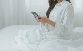 Happy freelance asian woman work on tablet on the hotel bed on travel trip. photo