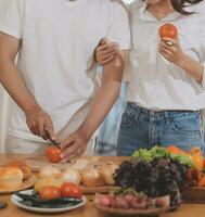 Handsome man sitting near his wife at kitchen. Family couple see social media, surf the web while sitting at kitchen table with generic laptop. Couple working with laptop at home photo