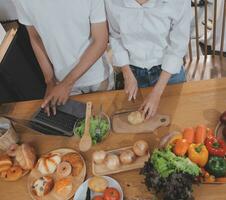 hermoso hombre sentado cerca su esposa a cocina. familia Pareja ver social medios de comunicación, navegar el web mientras sentado a cocina mesa con genérico ordenador portátil. Pareja trabajando con ordenador portátil a hogar foto