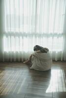 silhouette of woman sitting on the bed beside the windows with sunlight in the morning photo