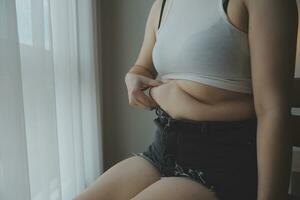 mujer gorda midiendo, mujer gorda gorda vientre gordito panzón deporte recreación cuidado de la salud perder grasa abdominal no hacer ejercicio concepto foto