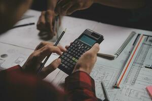 reunión de trabajo en equipo de ingenieros, trabajo de dibujo en la reunión de planos para el trabajo del proyecto con un socio en la construcción de modelos y herramientas de ingeniería en el concepto de sitio de trabajo, construcción y estructura. foto