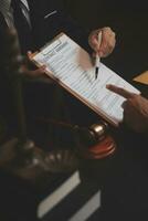 Business and lawyers discussing contract papers with brass scale on desk in office. Law, legal services, advice, justice and law concept picture with film grain effect photo