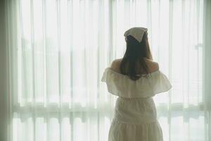 silhouette of woman sitting on the bed beside the windows with sunlight in the morning photo