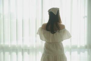 silhouette of woman sitting on the bed beside the windows with sunlight in the morning photo