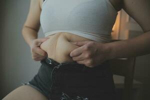 mujer gorda midiendo, mujer gorda gorda vientre gordito panzón deporte recreación cuidado de la salud perder grasa abdominal no hacer ejercicio concepto foto