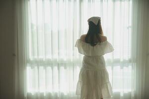 silueta de mujer sentado en el cama junto a el ventanas con luz de sol en el Mañana foto