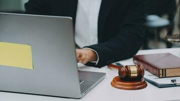 Justice and law concept.Male judge in a courtroom with the gavel, working with, computer and docking keyboard, eyeglasses, on table in morning light video