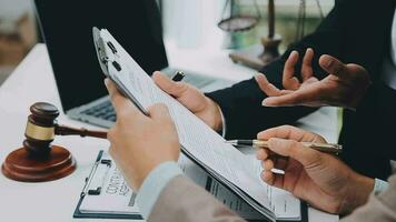 concetto di giustizia e diritto. giudice maschio in un'aula di tribunale con il martelletto, lavorando con computer e tastiera docking, occhiali, sul tavolo alla luce del mattino video