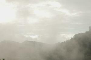 Mountain range with visible silhouettes through the morning blue fog. photo