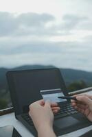 online payment, young woman holding credit card and typing on laptop photo