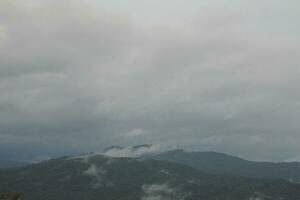 Mountain range with visible silhouettes through the morning blue fog. photo