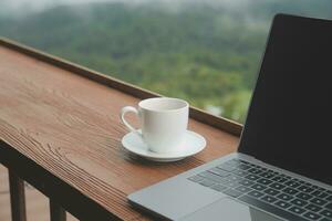 Computer Monitor, Keyboard, coffee cup and Mouse with Blank is on the work table at the sky mountain river and trees front view background. photo
