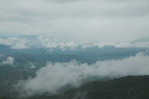 Beautiful panoramic view of fog and clouds in distant layers mountains range with blue sky in morning photo