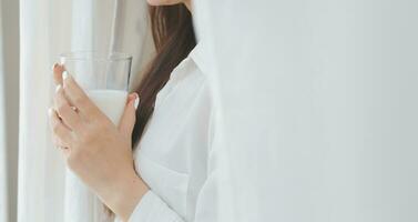 Happy young female in casual clothes smiling and looking at camera while using laptop on bed in bedroom at home photo