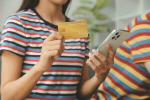 Young couple use credit card for online shopping on internet website at home. Number on the credit card is mock up. No personal information shown on the credit card. Online business shopping concept. photo