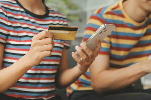 Young couple use credit card for online shopping on internet website at home. Number on the credit card is mock up. No personal information shown on the credit card. Online business shopping concept. photo