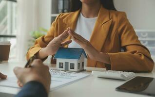 Real estate brokerage agent Deliver a sample of a model house to the customer, mortgage loan agreement Making lease and buy and sell house And contract home insurance mortgage loan concept photo