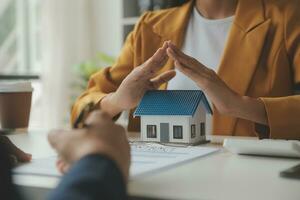 Real estate brokerage agent Deliver a sample of a model house to the customer, mortgage loan agreement Making lease and buy and sell house And contract home insurance mortgage loan concept photo