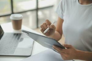 Asian Businesswoman Using laptop computer and working at office with calculator document on desk, doing planning analyzing the financial report, business plan investment, finance analysis concept. photo