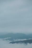 Mountain range with visible silhouettes through the morning blue fog. photo