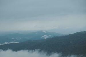 Mountain range with visible silhouettes through the morning blue fog. photo