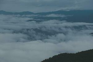 Mountain range with visible silhouettes through the morning blue fog. photo