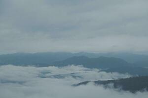 Mountain range with visible silhouettes through the morning blue fog. photo