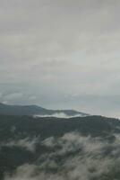 Mountain range with visible silhouettes through the morning blue fog. photo