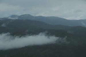 Mountain range with visible silhouettes through the morning blue fog. photo