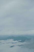 Mountain range with visible silhouettes through the morning blue fog. photo