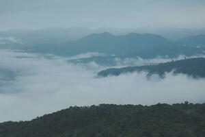Mountain range with visible silhouettes through the morning blue fog. photo