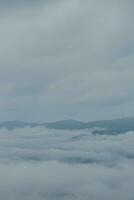 Mountain range with visible silhouettes through the morning blue fog. photo