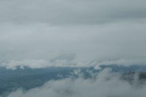 hermosa panorámico ver de niebla y nubes en distante capas montañas rango con azul cielo en Mañana foto