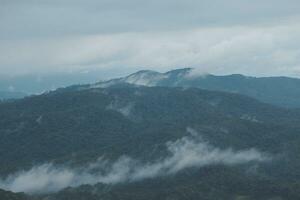 Mountain range with visible silhouettes through the morning blue fog. photo