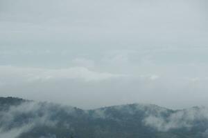 Mountain range with visible silhouettes through the morning blue fog. photo