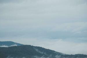 Mountain range with visible silhouettes through the morning blue fog. photo