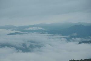 Mountain range with visible silhouettes through the morning blue fog. photo