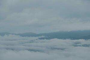 Mountain range with visible silhouettes through the morning blue fog. photo