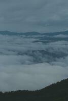 Mountain range with visible silhouettes through the morning blue fog. photo