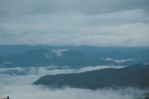 Mountain range with visible silhouettes through the morning blue fog. photo