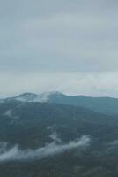 Mountain range with visible silhouettes through the morning blue fog. photo