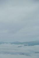 Mountain range with visible silhouettes through the morning blue fog. photo