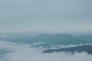 Mountain range with visible silhouettes through the morning blue fog. photo