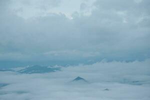Mountain range with visible silhouettes through the morning blue fog. photo