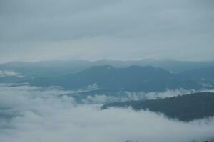 Mountain range with visible silhouettes through the morning blue fog. photo